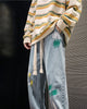Light blue paint-splatter jeans with a green and white paint patch on the hip and long cotton tapes