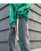 Washed gray paint-splatter jeans in motion, with the cream tapes hanging from the waist