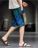 Navy and teal patchwork print shorts in motion, side view, showing the blue paisley panel