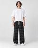 Man in black plaid wide-leg drawstring pants, white tee and white sneakers, full length