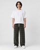 Man in army green plaid wide-leg drawstring pants, white tee and white sneakers, full length