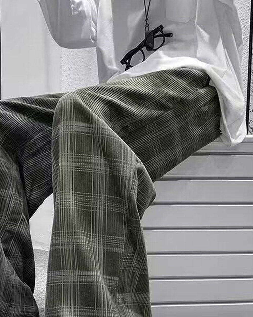 Army green plaid wide-leg pants worn seated, thigh to shin