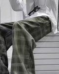 Army green plaid wide-leg pants worn seated, thigh to shin