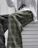 Army green plaid wide-leg pants worn seated, thigh to shin