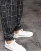 Close-up of the gathered elastic cuff with a frog-button knot on the black plaid harem pants