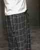 Close-up of the frog-button knot at the hip on the black plaid harem pants