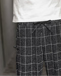 Close-up of the elastic drawcord waist and a frog-button knot on the black plaid harem pants