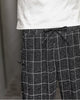 Close-up of the elastic drawcord waist and a frog-button knot on the black plaid harem pants