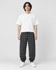 Model wearing the black plaid harem pants with a white tee and white sneakers, front view