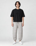 Model wearing the cream plaid harem pants with a black tee and white sneakers, front view