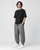 Model wearing the gray plaid harem pants with a black tee and white sneakers, three-quarter view