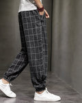 Black plaid harem pants in motion, side view, with the gathered cuff above white sneakers