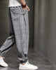 Gray plaid harem pants in motion, side view, with the gathered cuff above white sneakers
