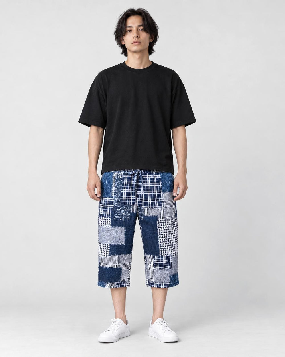 Model wearing the blue patchwork cropped pants with a black tee and white sneakers, front view