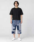 Model wearing the blue patchwork cropped pants with a black tee and white sneakers, front view