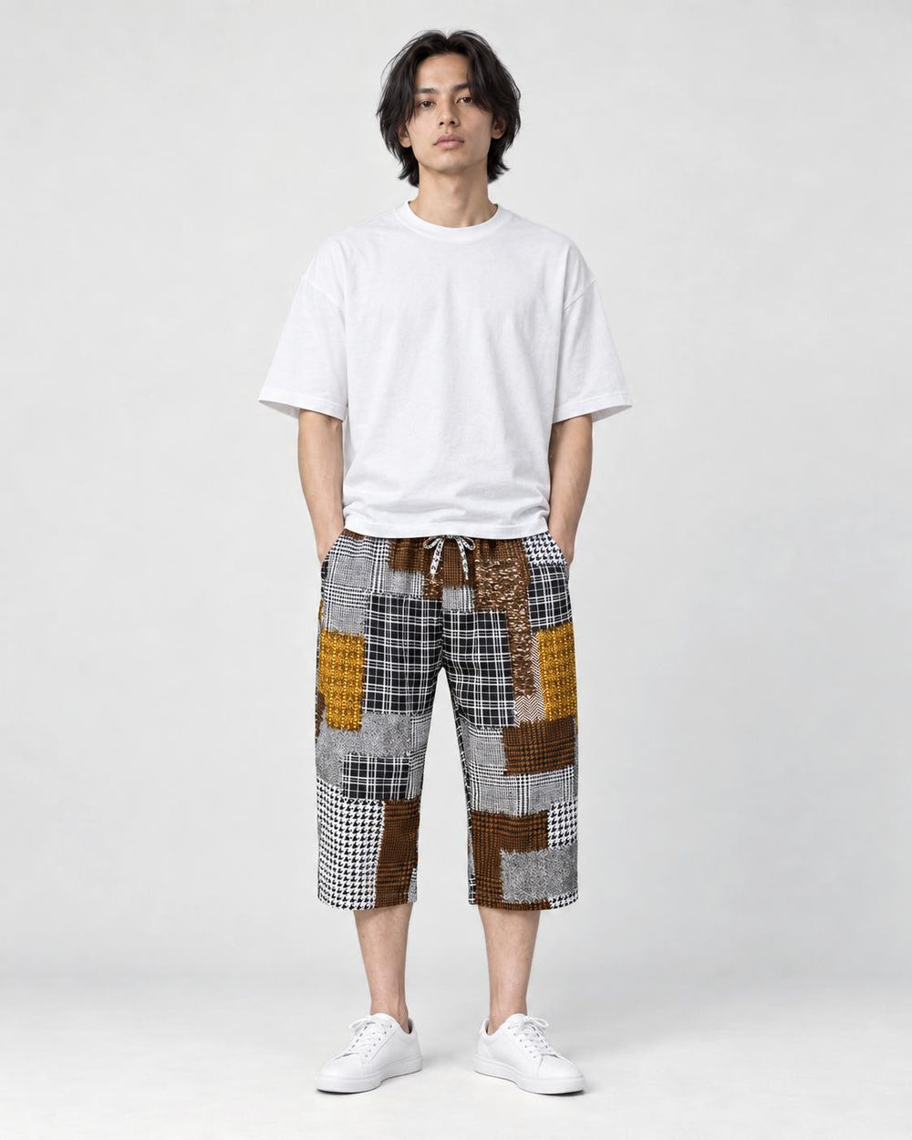 Model wearing the brown patchwork cropped pants with a white tee and white sneakers, front view