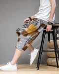 Man seated on a stool in the brown patchwork cropped pants, showing the mustard and plaid blocks