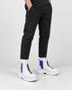 Legs of a man in the blue and white platform sneaker boots with a front zip, black trousers and white socks