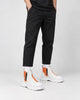 Legs of a man in the orange and white platform sneaker boots with a front zip, black trousers and white socks