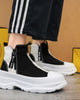 Black and white platform sneaker boots on foot with black striped track pants, three-quarter view