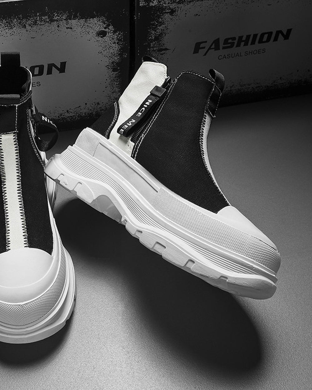 Black and white platform sneaker boots with a front zip and a NICE MEE pull, a studio pair on a gray floor