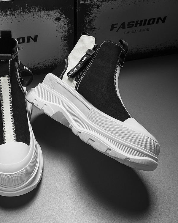 Black and white platform sneaker boots with a front zip and a NICE MEE pull, a studio pair on a gray floor