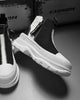 Black and white platform sneaker boots with a front zip and a NICE MEE pull, a studio pair on a gray floor