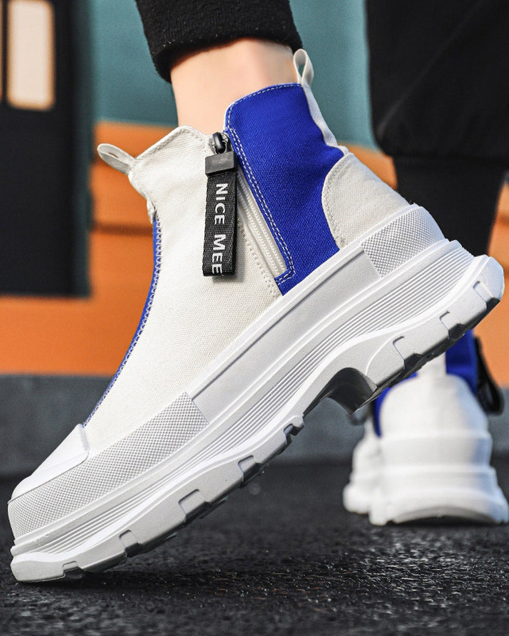 Blue and white platform sneaker boots on foot, close view of the zip pull and the chunky sole