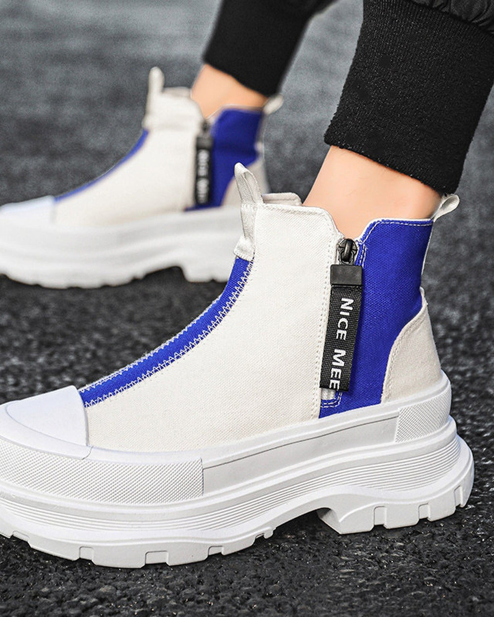 Blue and white platform sneaker boots on foot on a dark road, showing the royal-blue rear panel