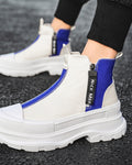 Blue and white platform sneaker boots on foot on a dark road, showing the royal-blue rear panel