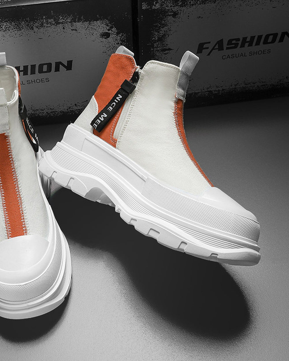 Orange and white platform sneaker boots with a front zip and a NICE MEE pull, a studio pair on a gray floor