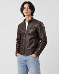 Model wearing the dark brown PU leather biker jacket with a white tee and light-wash jeans, three-quarter view