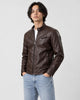 Model wearing the dark brown PU leather biker jacket with a white tee and light-wash jeans, three-quarter view