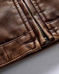 Close-up of the stitched hem band and the centre zip of the brown biker jacket