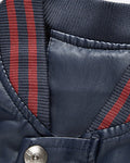 Close view of the striped rib collar and snap on the navy varsity jacket