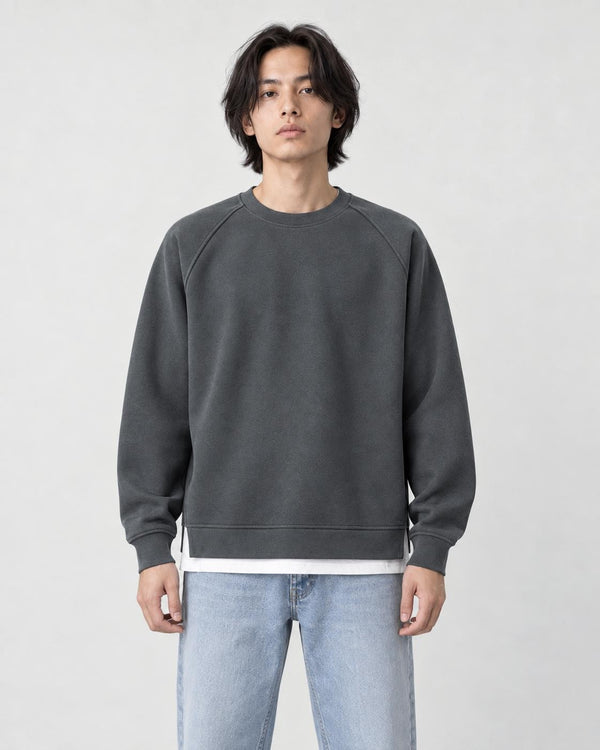 Model wearing the dark gray raglan sweatshirt with a white layered hem and light-wash jeans, front view