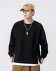 Black raglan sweatshirt with a white layer at the hem, worn with a tan cap and brown pants