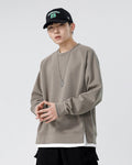 Taupe raglan sweatshirt with a white layer at the hem, worn with a black cap and black cargo pants
