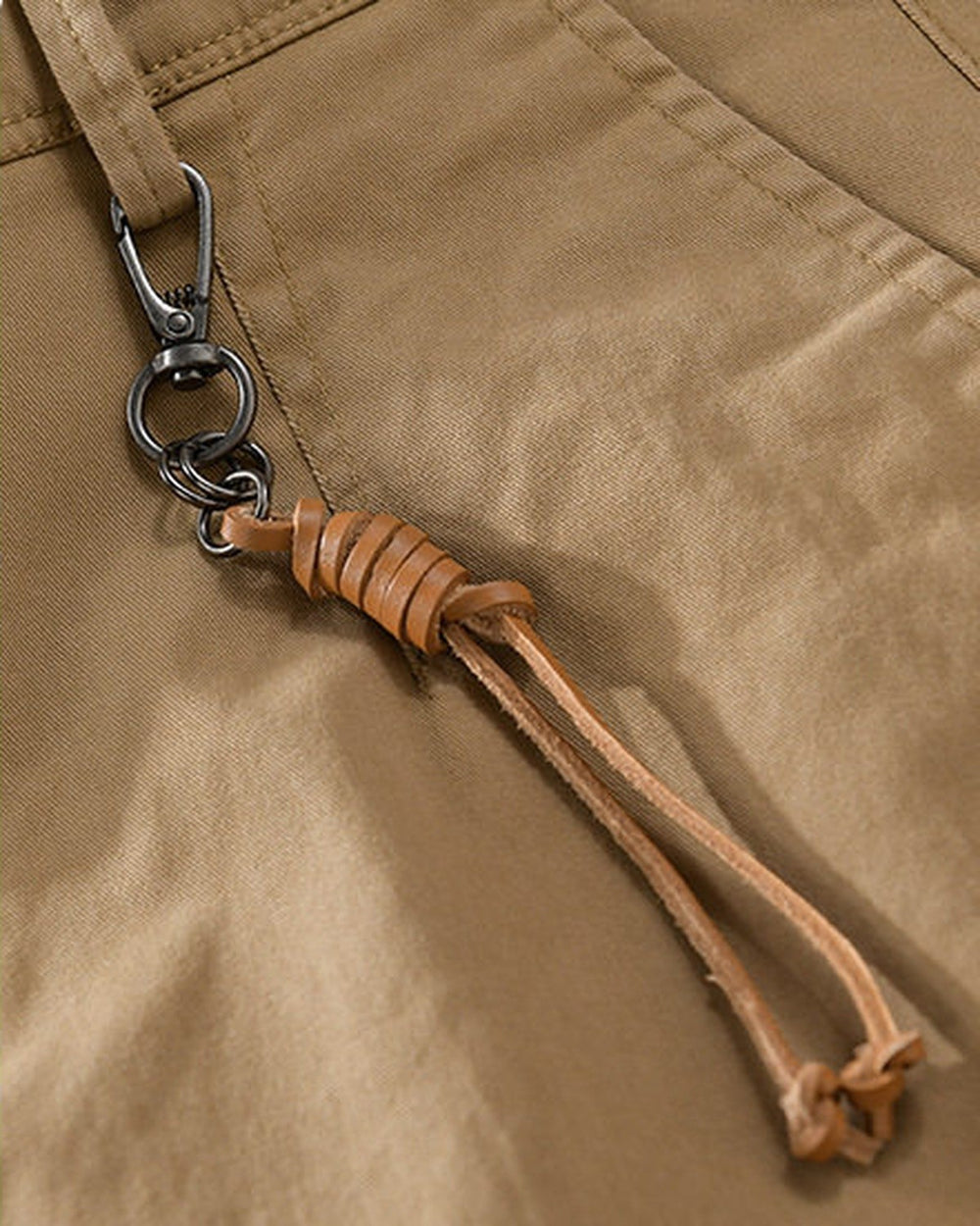 Close-up of the tan cord knotted to a metal snap hook on the belt loop of the khaki chinos