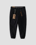 Black cuffed chinos with a tan cord and snap hook on the belt loop, flat view