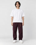 Model wearing the wine cuffed chinos with a white tee and off-white sneakers, front view