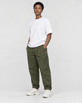 Model wearing the olive green cuffed chinos with a white tee and off-white sneakers, three-quarter view