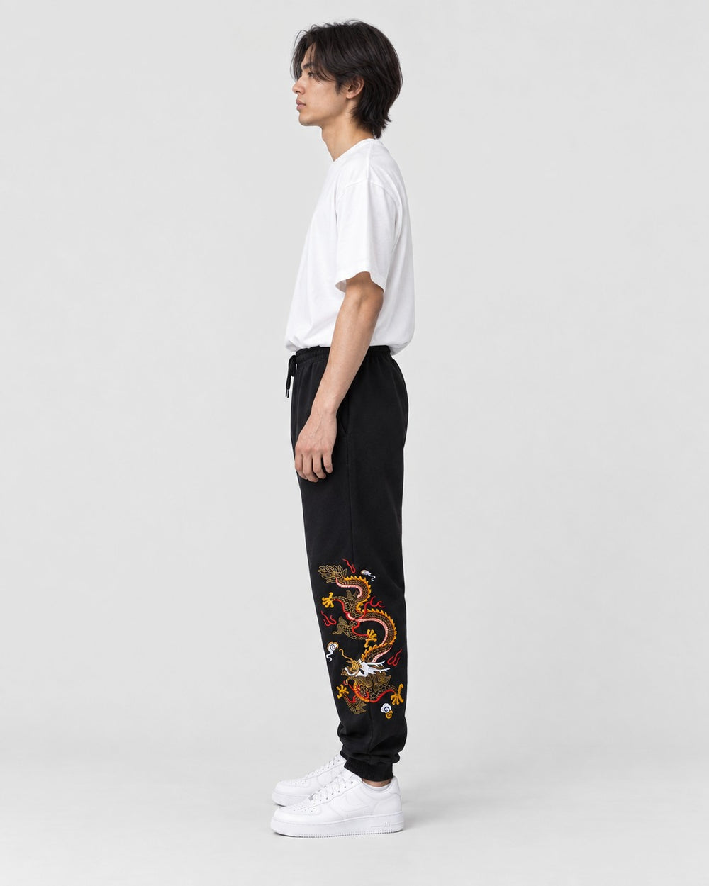 Model wearing the black gold dragon joggers with a white T-shirt, side view