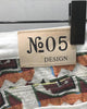 Close-up of the tan No.05 DESIGN patch and the woven jacquard at the back waistband