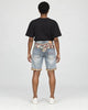 Model wearing the light blue washed denim shorts with a black tee, seen from behind, with the jacquard yoke