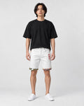 Model wearing the white stretch denim shorts with a black tee and white sneakers, front view