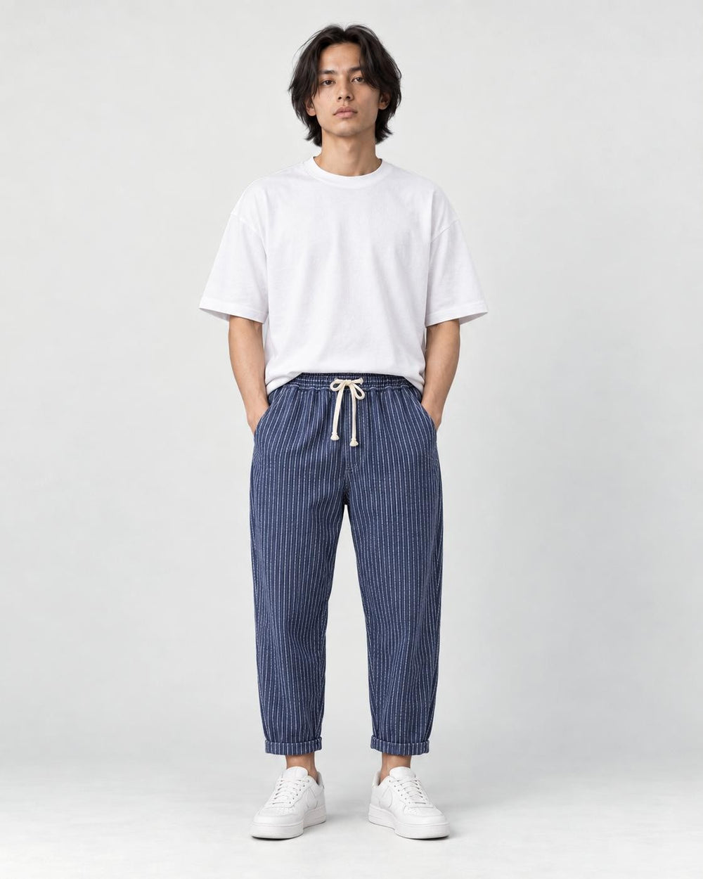 Model wearing the royal blue striped cropped pants with a white tee and off-white sneakers, front view