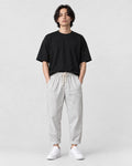 Model wearing the white striped cropped pants with a black tee and off-white sneakers, front view