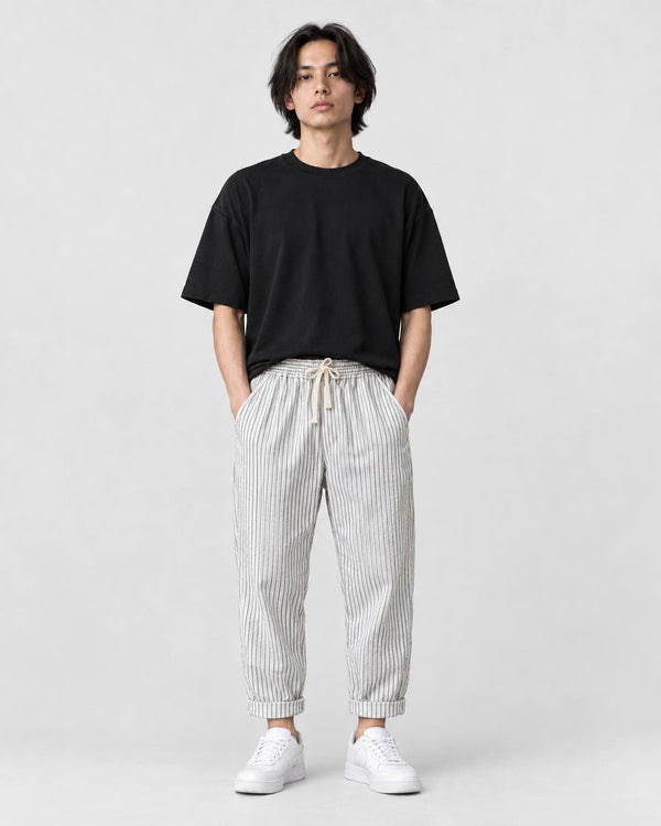 Model wearing the white striped cropped pants with a black tee and off-white sneakers, front view