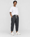 Model wearing the black striped cropped pants with a white tee and off-white sneakers, three-quarter view